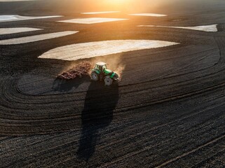 Aerial view of a tractor plowing a field at sunset