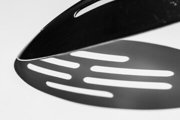 Abstract view of stainless steel metallic kitchen utensil with harsh shadow caused by sunlight on white surface