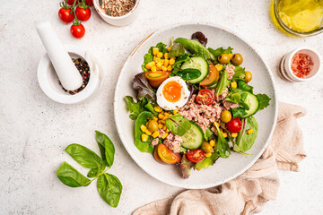 Tuna salad with tomatoes, cucumber, corn, olives , eggs and onion on white stone background, top view. High quality photo