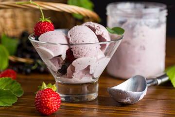 Blackcurrant ice cream with strawberries on wooden table
