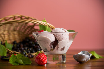 Blackcurrant ice cream with strawberries on pink background