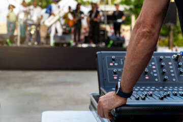 Sound technician controlling soundboard while music band plays on the stage on a music festival