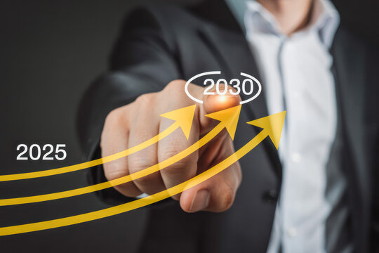 A businessman in a suit points at a rising arrow marked with years 2025 to 2030, symbolizing future business growth and success. The visual indicates strategic planning and forward-thinking.