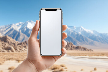 A hand holding a smartphone with the natural beauty of the mountains and desert in the background. A blank display creates the perfect canvas for your digital content.