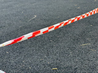 Bright safety tape delineates a restricted area on a gravel surface, signaling caution at a...