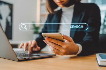 A person uses a laptop and smartphone at a desk, with a floating search bar overlay. The image represents multitasking in digital workspaces, emphasizing online search and connectivity.