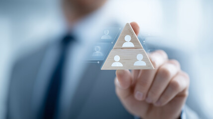 Close-up triangle of wooden figures, hand in motion, icons hover for structured HR strategy