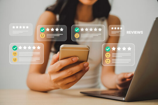 A woman checks reviews on her smartphone while using a laptop, highlighted by overlaying graphics of star ratings and smiley faces, indicating user feedback and satisfaction in an online context.