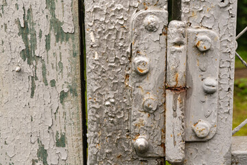 Rustic weathered wooden gate with peeling paint and rusty metal hinges