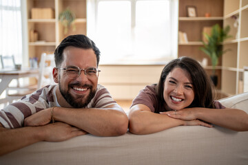 Happy couple smiling and leaning on sofa in living room