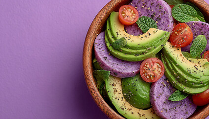 Top view of a fresh salad with avocado, tomato, and lemon in a bowl on a purple background with copy space for your text or message