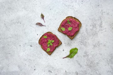 A colorful beetroot spread on toasted brown bread, garnished with fresh herbs, is a healthy, tasty...