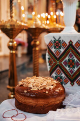 Decorative traditional bread with ornaments, placed in orthodox church setting with lit candles for...