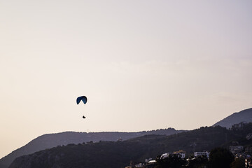 Paraglider Soaring Over Scenic Mountainous Landscape at Sunset Time