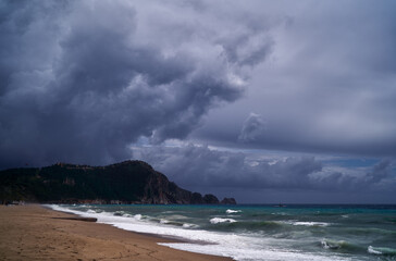 Stormy Seaside Landscape with Waves and Moody Sky over Coastal Mountain