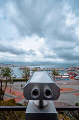 Observation Binoculars Overlooking a Scenic Harbor with Cloudy Sky