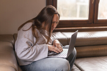 A woman with poor eyesight looks at the screen of her laptop, which she holds on her lap
