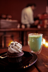 Closeup of a Delicious Chocolate Cupcake and a Green Tea Latte in a Café