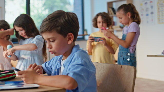 Children enjoying school break sitting classroom with gadgets. Little schoolboy - Powered by Adobe