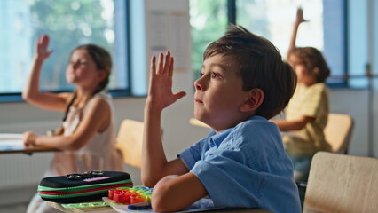 Group pupils raising hands to answer question teacher closeup. Active children