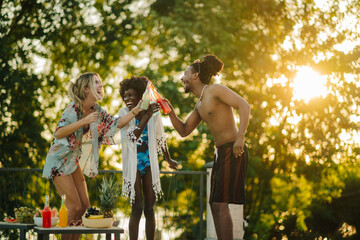 Friends toasting with bottles of juice at sunset pool party