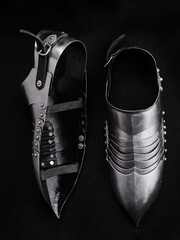 Close-up of finely crafted historical foot armor, showcasing detailed metallic designs and...