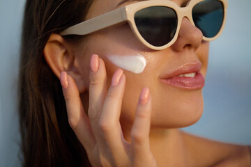 Woman with beautiful face touching healthy facial skin portrait and uses sunscreen. Beauty close up...