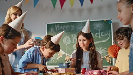 Cheerful children celebrating birthday in classroom with colorful decorations.
