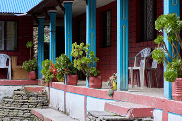 A charming trekking lodge located in the Annapurna region of Nepal showcases colorful blue pillars...