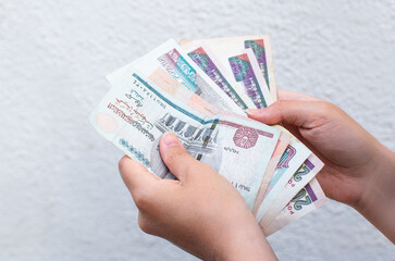 counting Egyptian pound banknotes against a white wall. Financial concept with local currency, budgeting or saving money in Egypt.