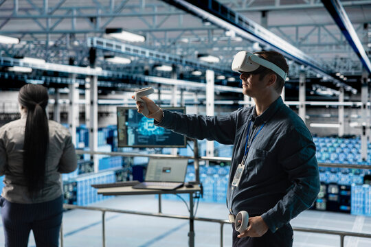 Server room worker visualizing server architecture using VR gear in AI data center. Data center engineer using virtual reality tech and artificial intelligence to do infrastructure diagnostics