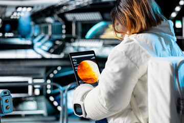Close up of astronaut in orbital station analyzing Mars planetary metrics using tablet. Crew member...