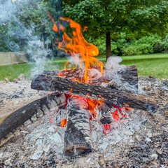 Small campfire with flames, smoke, and ash with square crop