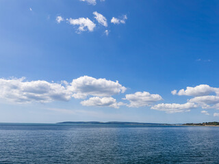 Fototapeta premium Bournemouth, UK - June 2nd 2025: Blue sky and clouds above Poole Bay.
