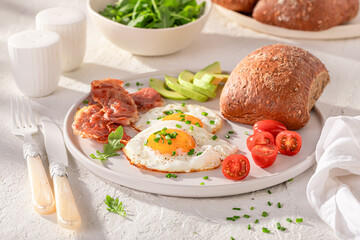 Tasty and american breakfast with egg, tomato and rolls.