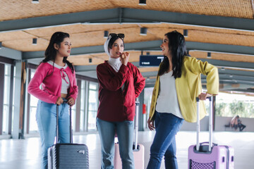 Stylish trio of young women at the airport discussing their trav