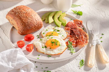 British and homemade breakfast with avocado, fied eggs and bun.