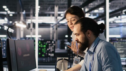 Anxious technicians in data center reacting to system lockdown caused by ransomware alert. IT...