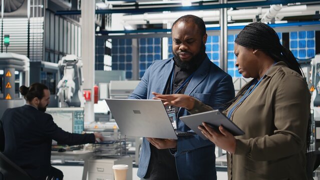 African american business associates engineers gathering for discussion in solar manufacturing plant, planning future developments in renewable energy and industrial operations. Camera A.