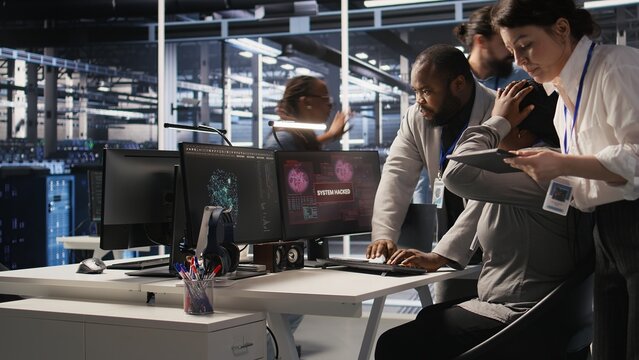 Scared data center technicians reacting to virus warning on PC display, scrambling to launch emergency response protocol. Admins run around server room, urgently trying to fix hacked systems, camera A - Powered by Adobe