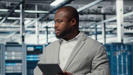 IT expert in industrial data center analyzing infrastructure performance, minimizing downtime and...