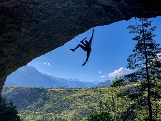 SILHOUETTE: Climber hangs from a rope after falling, with a vast mountain valley and village spread...