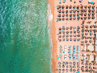 Aerial panorama landscape of coastline beach with umbrellas and sun loungers and crystal clear turquoise blue sea water, summer vacation in Greece islands