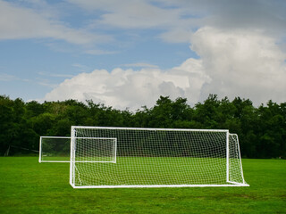 Clean cut football or soccer training ground with two goal posts, dark trees and dramatic sky in the background. Popular world sport. Team development area. Nobody.