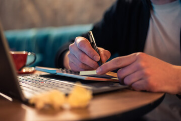 Close cropped image of a business man writing in a notebook with crumpled papers on the desk while...