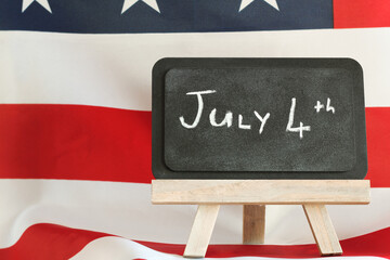 “July 4th” Message on Chalkboard with American Flag Background – Independence Day Celebration...