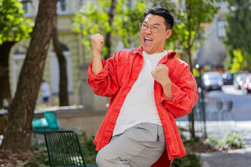 Asian middle-aged man shouting celebrating success winning goal achievement good news lottery...