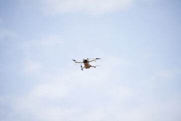 White drone flying, blurred green trees in background