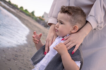 Mother hugs her son beside the lake.