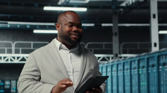 System administrator walking in server farm deploying infrastructure for efficient data analysis. Worker using device in dat a center in managing storage systems for datasets, camera B